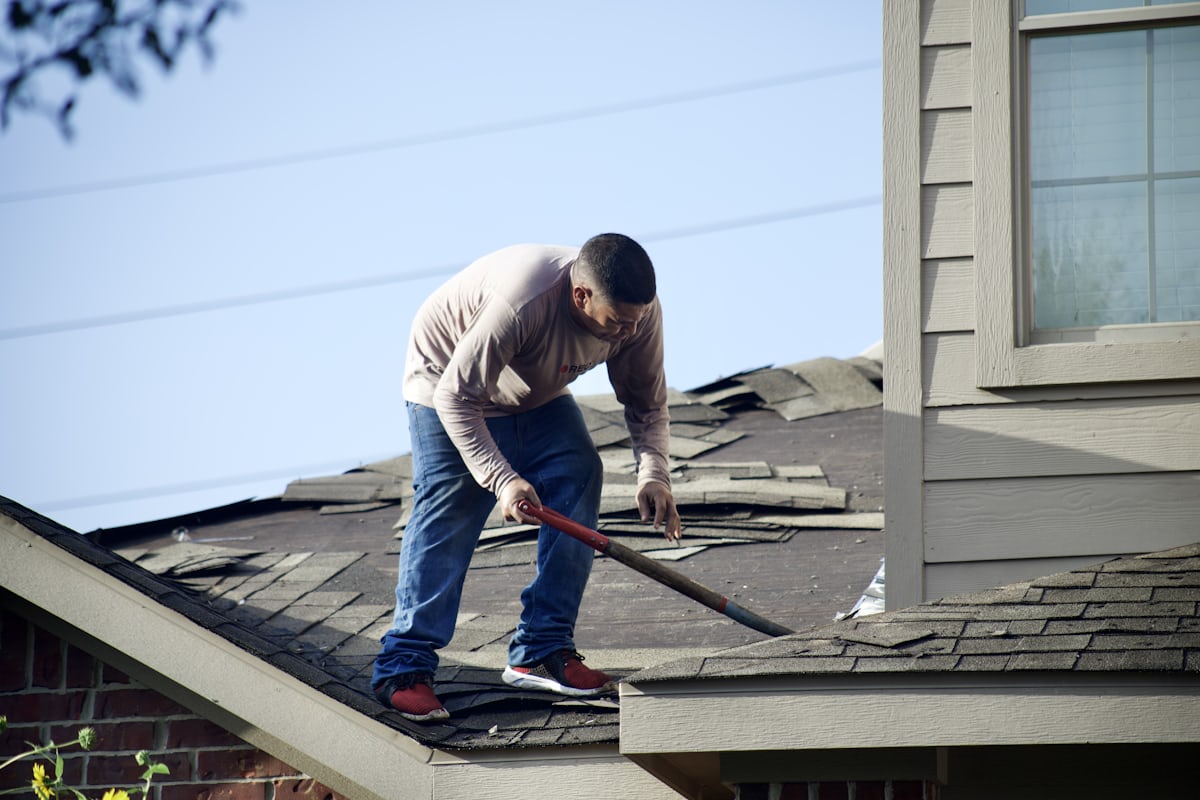 Roofer conducting roof inspection using best roofing estimating software with aerial measurements on a mobile device